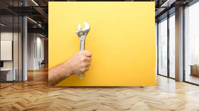 cropped view of man holding spanner on yellow background Wall mural