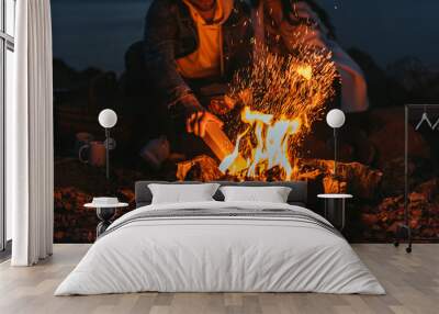 cropped view of man putting log in bonfire near girl Wall mural