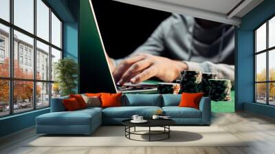 cropped view of man typing on laptop near poker chips isolated on black Wall mural