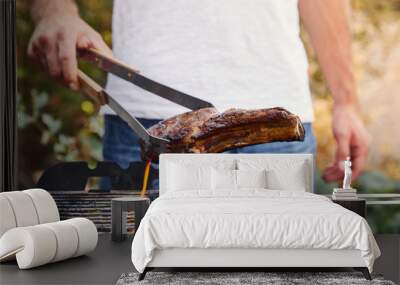 cropped view of man with tweezers grilling meat on barbecue grid Wall mural