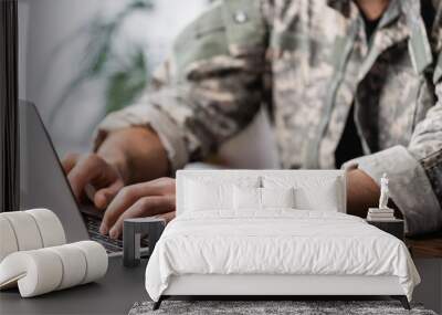 Cropped view of military man using laptop on desk Wall mural