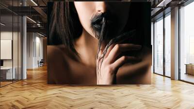 Cropped view of nude woman with black painted lips and hand showing silence gesture isolated on black Wall mural