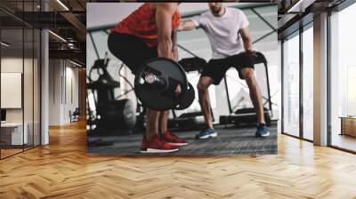 cropped view of trainer supporting american sportsman lifting barbell Wall mural