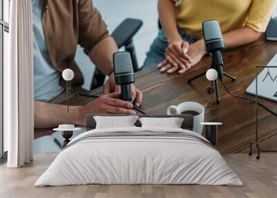 cropped view of two radio hosts sitting at workplace near microphones Wall mural