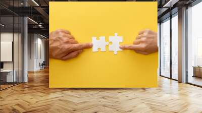 cropped view of woman and man matching pieces of white jigsaw puzzle on yellow background Wall mural