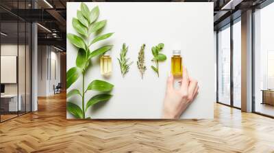 Cropped view of woman holding bottle with essential oil on white background Wall mural