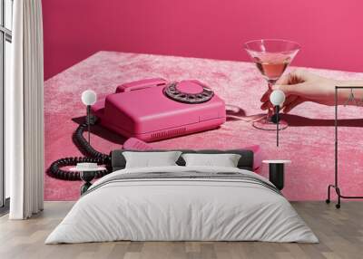 cropped view of woman holding glass of rose wine near retro phone on velour cloth isolated on pink,  Wall mural