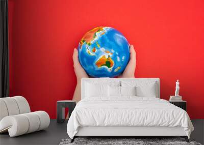 Cropped view of woman holding globe on red background, global warming concept Wall mural