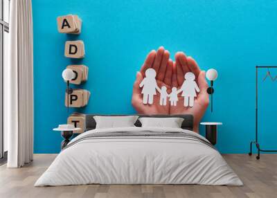 cropped view of woman holding paper cut lesbian family near blocks with adopt lettering on blue background Wall mural