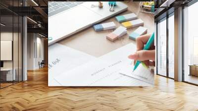 cropped view of woman holding pen in hand, writing notes in planners, sitting behind wooden table with flowers and stationery Wall mural