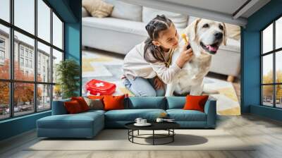 cute girl in casual attire playing doctor with labrador in modern living room, toy first aid kit Wall mural