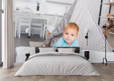 cute toddler boy standing near bed, smiling and looking at camera in apartment Wall mural