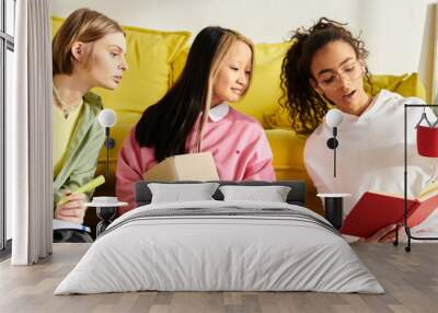 Diverse group of young women laughing and studying on top of a bright yellow couch in a cozy home setting. Wall mural