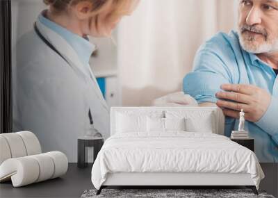 doctor in white coat making injection to senior patient in clinic Wall mural