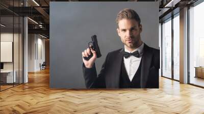 elegant businessman looking at camera while holding weapon on grey background with smoke Wall mural