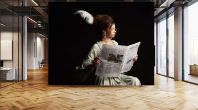 elegant woman in pastel grey vintage dress reading travel life newspaper isolated on black Wall mural