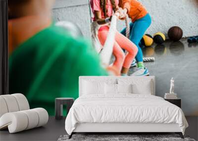 Enthusiastic kids playing tug of war in gym Wall mural