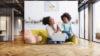 excited african american mom and child giving high five near laptop at home Wall mural