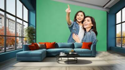 excited daughter pointing with finger while happy mother looking up isolated on green Wall mural