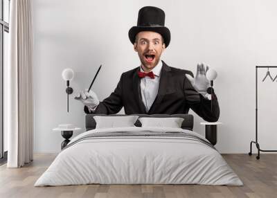 excited magician in suit and hat holding wand, isolated on grey Wall mural