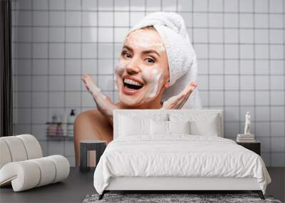 excited woman with naked shoulders applying foam cleanser in bathroom Wall mural