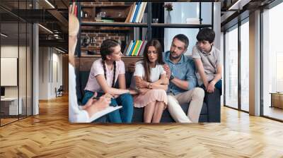 family cheering up woman on therapy session by female counselor in office Wall mural