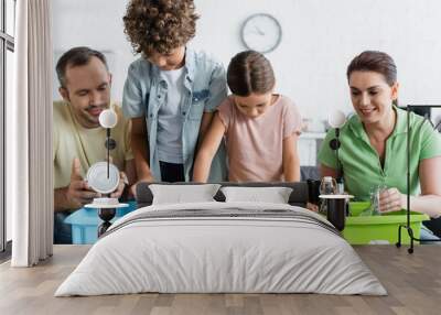 Family with kids sorting trash in boxes with recycle sign at home Wall mural