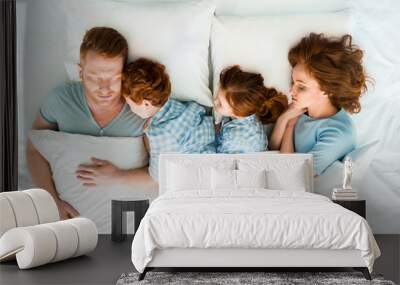 family with two children sleeping together in bed Wall mural