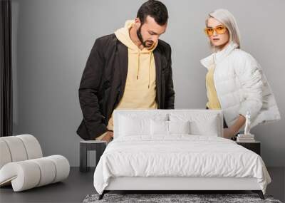 fashionable couple of models posing with hands in pockets isolated on grey background Wall mural