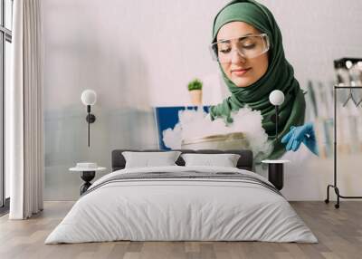 female muslim scientist in goggles during experiment with dry ice in laboratory Wall mural