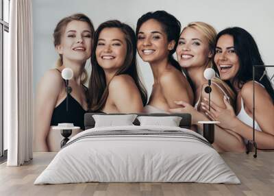 five sexy multiethnic young women in underwear embracing and smiling isolated on grey Wall mural