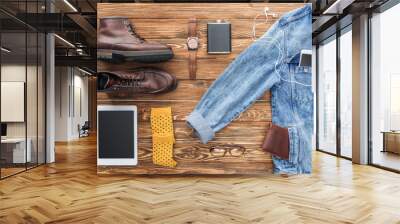 Flat lay of boots, denim jacket and digital devices on wooden background Wall mural