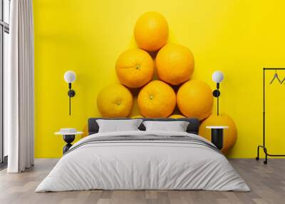 Flat lay with oranges in triangle shape on yellow background. Wall mural