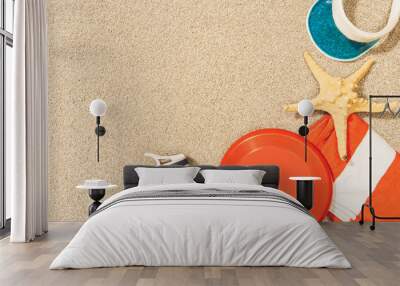 flat lay with water bottle, towel, cap, frisbee and sea star on sand Wall mural