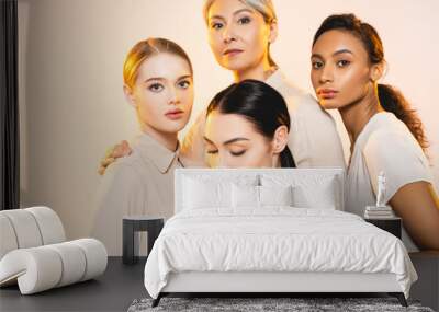 four attractive multicultural women with makeup isolated on beige Wall mural