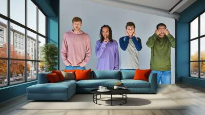 four friends in casual bright attire standing and gesturing on grey background, cultural diversity Wall mural