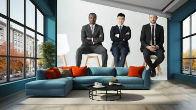 front view of multiethnic businessmen sitting on chairs isolated on white, multicultural business team concept Wall mural