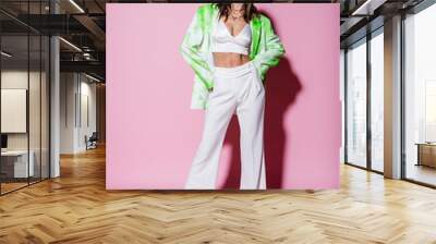 full length of brunette woman in stylish outfit posing with hands on hips on pink Wall mural