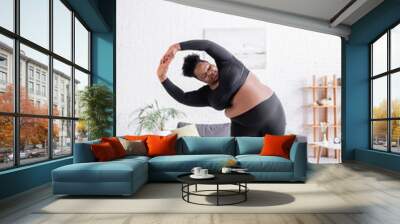 full length of curly african american plus size woman in sportswear exercising on fitness mat Wall mural