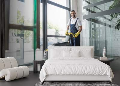 full length of professional cleaner with electrical floor scrubber machine smiling at camera. Wall mural