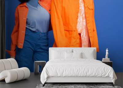 Full length of stylish multiethnic couple in jackets posing on blue background. Wall mural