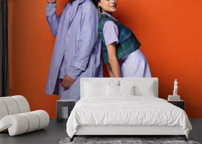 full length of trendy african american woman smiling while leaning on stylish man on orange Wall mural