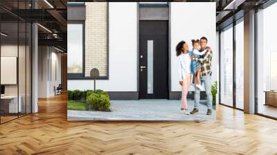 full length view of african american family standing near new house while father holding kid and looking at camera Wall mural