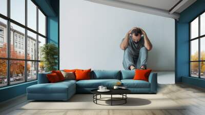 full length view of scared depressed man sitting with hands behind head on floor Wall mural