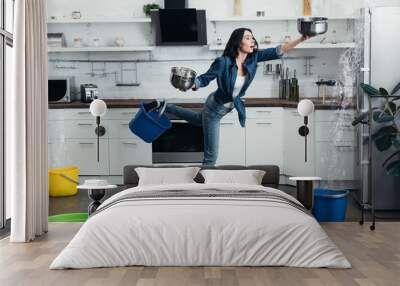 Full length view of shoked woman in jeans dealing with water leak in kitchen Wall mural