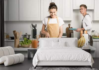 girlfriend cooking salad and cutting tomatoes in kitchen Wall mural