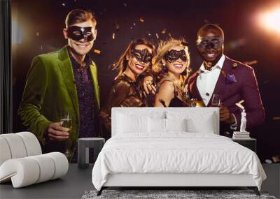 glamorous multiethnic friends in carnival masks holding champagne glasses and celebrating new year on party Wall mural