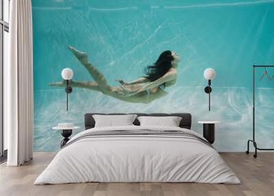 graceful young woman in white swimsuit diving in swimming pool Wall mural