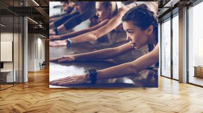 group of athletic young people in sportswear stretching at the gym, group fitness concept Wall mural