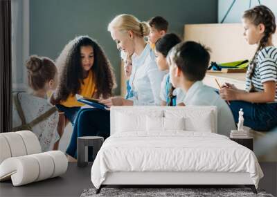 group of schoolchildren listening to their teacher while sitting on tribune Wall mural